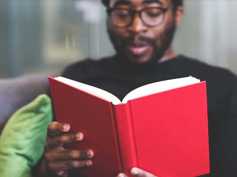 Man reading a red book from the CCS library