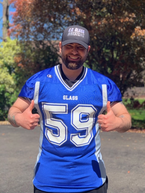 Smiling man in a blue football jersey with number 59 and 'GLASS' on the chest, giving thumbs up outdoors with fall foliage in the background. Teaching 9/11 as a Christian: How CCS Professor Bryce Woerner Landed on the Front Page